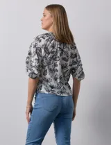 Blusa de gasa blanca con estampado de hojas en azul marino, cuello a la base con escote en V y botones, y mangas cortas abullonadas.