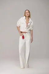 Chaqueta de sarja color blanco con costuras en contraste color rojo, corte cropped, cuello camisero, cierre frontal con botones y bolsillos delanteros con solapa.