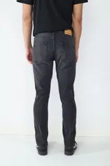 Jean de corte slim fit en color negro lavado, con diseño clásico de cinco bolsillos, cierre frontal con botón y cremallera.