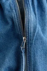Campera bomber oversize de denim azul, con cuello elevado fruncido, cierre frontal y bolsillos laterales. Cuenta con mangas raglán y elásticos en puños y bajo.