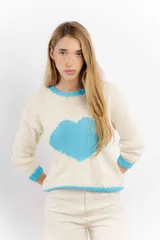 Buzo de lana tejido a mano, de color crudo con diseño de corazón grande en el centro, cuello redondo, puños y ruedo en color celeste.