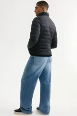 Campera puffer liviana de corte ajustado, con cuello elevado y cierre frontal. Presenta diseño acolchado horizontal, bolsillos laterales ocultos y acabado repelente al agua.