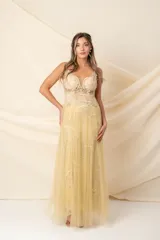 Vestido largo de tul bordado color dorado, con corsé transparente, breteles finos bordados, cintura con alforzas y bordado en hilo de seda, y falda de tul bordado con sobrefalda de tul plisado.