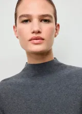 Jersey de punto fino color gris con cuello perkins, diseño entallado y manga larga.