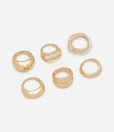Kit de seis anillos para mujer de diseños variados, que incluye piezas anchas y lisas de acabado metálico dorado, un anillo doble con relieve central, y un anillo con centro de resina transparente. Elaborados en metal.