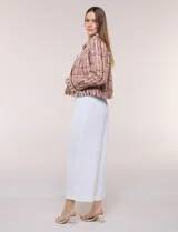 Chaqueta de tweed en tonos rosados, marrones y blancos, con hilos metalizados y lentejuelas brillantes. Presenta cuello camisero, cierre frontal con botones metálicos dorados, bolsillos frontales en el pecho, mangas largas y terminaciones desflecadas.