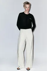 Chaqueta de punto de efecto doble capa color negro, con cuello redondo y ribete blanco, manga larga y cierre frontal con botones. Cuenta con un bolsillo de parche en el pecho con detalle en contraste.