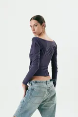 Top azul marino de manga larga con escote asimétrico y frunces laterales.