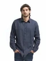 Camisa de manga larga color azul oscuro, confeccionada en mezcla de lino y viscosa, con cuello camisero y botones frontales. Presenta un botón en la manga para sujetar el puño remangado.