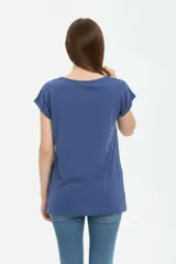 Remera de algodón negra, de corte holgado, con cuello redondo a la base y detalle de estampado floral en el hombro izquierdo.