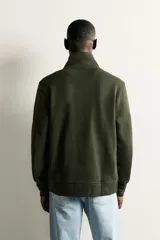 Chaqueta regular fit de cuello subido, confeccionada en tejido técnico interlock de algodón con elasticidad. Presenta cierre frontal con cremallera, manga larga con puños en rib y bolsillos de vivo en la cadera.