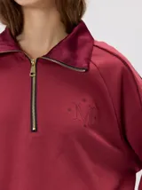Buzo verde militar de algodón suave, de calce oversize, con cuello alto y cierre frontal parcial metalizado. Cuenta con bolsillos laterales con cierre y puños y ruedo elastizados.