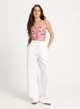 Crop top con estampado floral en tonos fucsia y blanco, breteles finos con lazos en los hombros y detalle de franjas horizontales en el bajo.