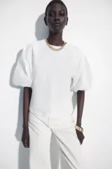 Camiseta blanca de corte slim fit con cuello redondo y mangas cortas abullonadas en tejido a tono.