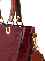 Cartera de mano de estructura rígida con textura símil cocodrilo en color bordó, con manijas superiores cortas en tono tostado y herrajes metálicos dorados.