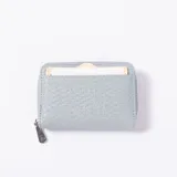 Monedero de cuero sintético con textura trenzada, color celeste, con cierre perimetral y tarjetero exterior.