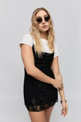 Vestido corto de encaje negro con breteles finos y corte ajustado al cuerpo.
