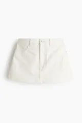 Short pollera de cinco bolsillos en denim de algodón color blanco, con diseño de tiro alto, cierre frontal y botón metálico.