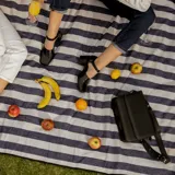 Zapato de cuero vacuno color gris topo, con talón descubierto y pulsera con hebilla. Tiene taco de madera forrado en cuero y suela de goma. La horma es de punta cuadrada, ancha y cómoda.