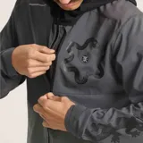 Campera deportiva gris con capucha negra, cierre frontal completo, bolsillo en el pecho con cierre y logo estampado en el hombro.