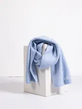 Bufanda de punto acanalado en color celeste, con textura suave y etiqueta de marca en el extremo.
