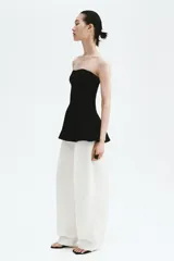 Top strapless largo en punto tupido color negro, con costuras enlazadas y peplum acampanado.