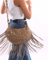 Bolso de hombro estilo boho confeccionado en gamuza color bordó. Presenta un diseño semicircular decorado con tachas metálicas plateadas dispuestas en líneas curvas y flecos largos en todo el borde inferior. Cuenta con cierre superior y correa ajustable para llevar al hombro.