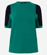 Blusa de viscosa con cuello redondo y mangas cortas. Presenta un diseño de bloques de color contrastantes, con cuerpo en tono malva y mangas en color negro, destacando por sus recortes asimétricos en la sisa.