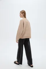 Sweater holgado de punto color beige con cuello redondo a la base y mangas largas raglán.