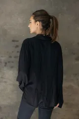 Camisa de corte relajado y caída fluida, con cuello clásico, mangas largas con puños anchos y cierre frontal con botones a contraste.