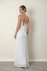 Vestido largo de encaje blanco, con breteles finos cruzados en la espalda y escote halter con abertura en forma de gota.