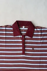 Camiseta polo Rotunda modelo Risen de manga corta, con diseño a rayas horizontales en celeste, bordó y líneas finas amarillas. Cuenta con cuello y solapa de botones en color bordó, y detalle de letra "R" bordada en el pecho.