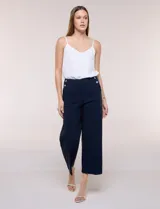 Pantalón crop blanco de corte recto con cintura ancha y botones decorativos laterales. Cuenta con bolsillos y pinzas frontales.