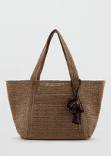 Bolso tipo tote color marrón, confeccionado en tejido de fibra natural de papel, con asas largas de hombro y detalle de charm colgante con flecos.