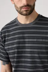 Remera de manga corta con cuello redondo, confeccionada en tejido de algodón con diseño de rayas horizontales en tonos grises y negros. Presenta el logo de la marca bordado discretamente en el pecho.