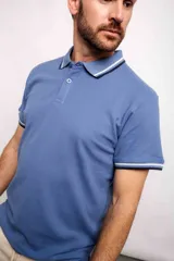 Remera polo blanca de corte regular, con cuello y mangas con detalles de doble línea en azul y negro.