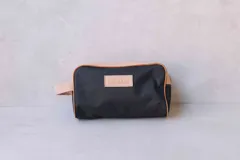 Neceser de lona verde con detalles en cuero color beige y etiqueta con logo de la marca Sierra Mora.