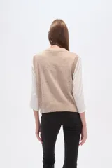 Chaleco de punto sin mangas en color beige con efecto confetti y diseño de jacquard frontal en color negro con motivos de herradura, luna y pájaro. Cuenta con cuello redondo y acabados acanalados.