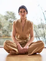 Mono color arena de lino, con cuello mao, cierre frontal con cremallera, mangas cortas y cinturón de lazo.