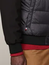 Campera bomber negra con frente acolchado y mangas de tejido liso. Cuello, puños y bajo de punto canalé. Cierre frontal con cremallera. Logo de Tommy Hilfiger bordado en el pecho.