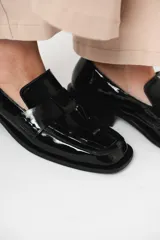 Mocasín de cuero charol negro con diseño enrejillado en la capellada y horma cuadrada.