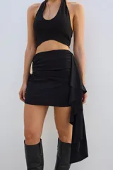 Minifalda negra con drapeado lateral y aplique metálico dorado.