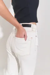 Jean de corte oxford y tiro bajo, confeccionado en denim blanco. Presenta diseño de cinco bolsillos, cierre frontal con cremallera y botón metálico, y costuras a contratono.