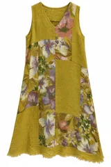 Vestido midi sin mangas de lino con escote en V y diseño de paneles en bloques que combinan tela lisa en color mostaza y fragmentos con estampado floreado. Presenta un dobladillo desmechado con flecos en la parte inferior.