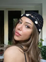 Gorro de crochet negro con diseño calado y apliques de caracoles blancos.