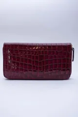 Billetera rectangular con cierre perimetral, confeccionada en cuero con textura de reptil. Cuenta con múltiples compartimentos internos para tarjetas, documentos y billetes, además de un bolsillo interior con cierre para monedas.