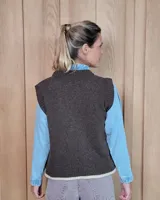 Chaleco tejido de punto con diseño abstracto en bloques de color marrón y turquesa, con cuello redondo y terminaciones acanaladas.