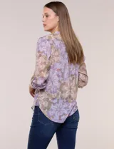 Blusa de gasa estampada de la marca Zac & Rachel, en tonos violeta y marrón. Presenta cuello a la base con escote en V y botones frontales, detalles de plisado en la delantera y mangas largas con sistema para regular su largo mediante presilla y botón.