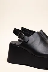 Sandalias con plataforma color marrón, con capellada envolvente, pulsera trasera ajustable y hebilla metálica.