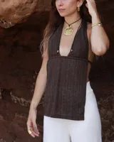 Collar artesanal con dije central de metal con textura orgánica irregular que evoca una ostra. El dije está montado sobre un cordón de algodón natural, permitiendo un uso versátil y regulable.